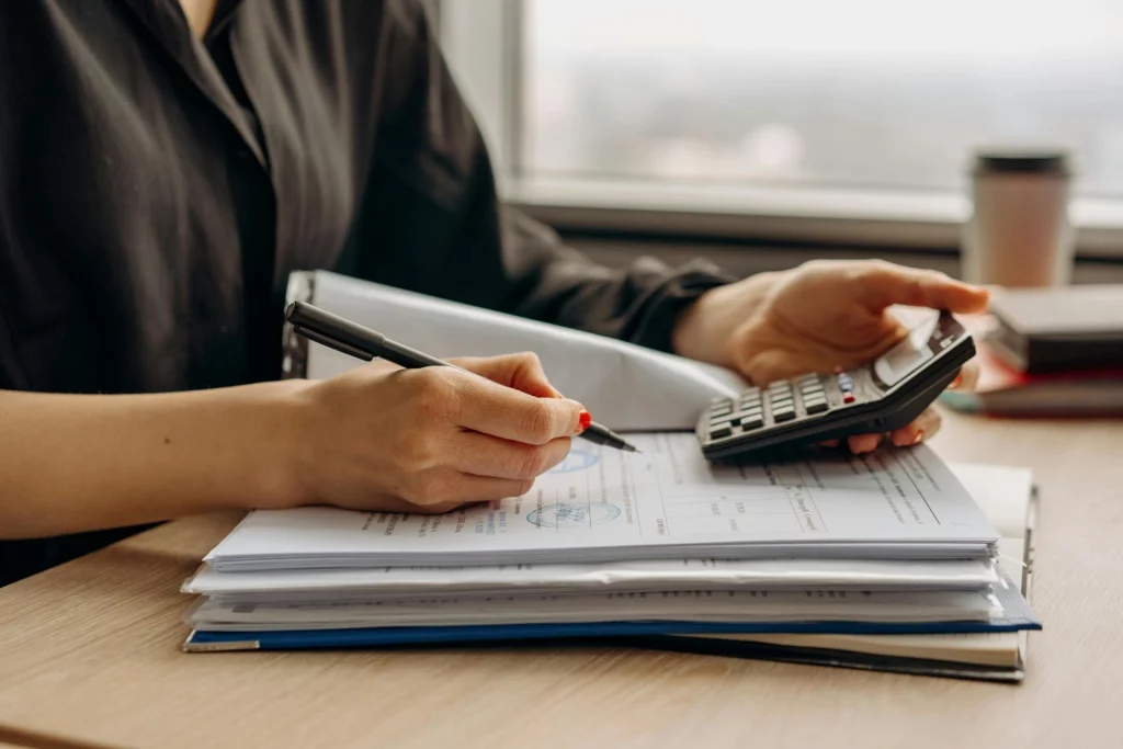 Mãos escrevendo em um caderno sobre uma mesa, demonstrando a adaptação às mudanças do ajuste SINIEF 43/2023.